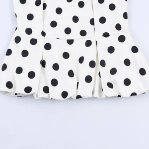 Detailed close-up of white and black polka dot peplum hem with sharp stitching