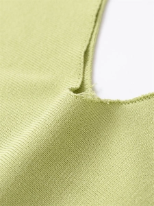 Macro view of grass green fine knit fabric with vertical ribbing and distressed hem detail