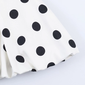 Detailed macro view of white fabric with large black polka dot print and woven texture