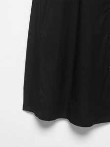 Vue détaillée de la robe noire en popeline montrant la texture du tissu et les boutons