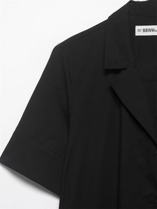 Détail du col à revers et des coutures précises sur une robe courte en popeline noire