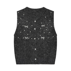 Detailed close-up of dark grey knit vest with shimmering sequins and pearl bow accents