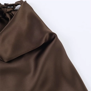 Detailed close-up of dark brown satin dress with pleated texture and braided strap details