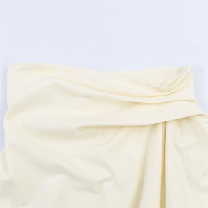 Detail of cream backless top showing pleated texture and asymmetric draping fabric
