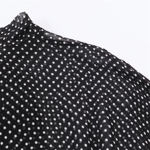Detail of elegant black polka dot chiffon shirt showing high neckline and smooth fabric