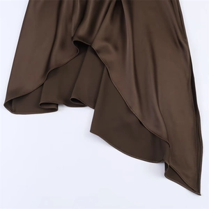 Detail of a brown satin dress featuring irregular asymmetrical hemline and smooth finish