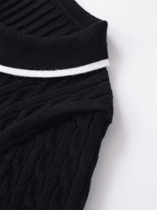 Détail macro d'un pull noir en maille torsadée avec encolure à rayures blanches