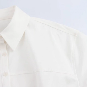 Detail view of the white shirt dress collar and clear buttons with fine fabric texture