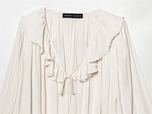 Detailed close-up of beige ruffled collar and V-neckline tie on the casual blouse