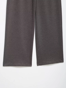 Detailed view of dark grey wide leg trousers showing refined texture and hem stitching