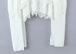 Detailed view of white chiffon top featuring intricate floral lace hem and sleeve edges