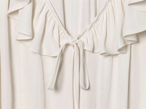 Close-up of ivory ruffle V-neckline with delicate tie detail and soft chiffon texture