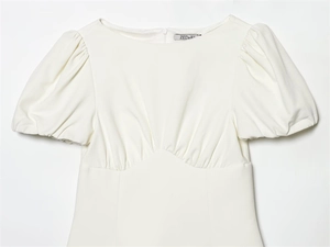 Détail de robe blanche à manches bouffantes avec taille empire plissée et zip invisible