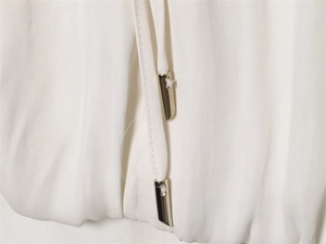 Detail view of white chiffon shirt showing silver metal aglets on drawstrings