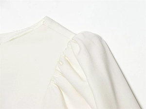 Détail de la robe blanche montrant les manches bouffantes et les plis sur l'épaule
