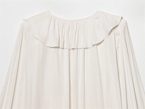 Detail of elegant ruffled collar and pleated silk texture on white women shirt
