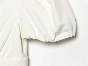 Détail du poignet à manches bouffantes blanches avec texture tissée sur robe chic