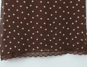 Détail d'une robe en mousseline marron à pois avec dentelle ondulée délicate au bord