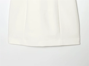 Vue macro détaillée de l'ourlet de la robe blanche avec coutures précises et tissu de qualité
