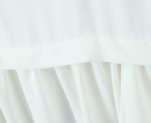 Macro detail of high-density white chiffon fabric with pleated hem and fine stitching