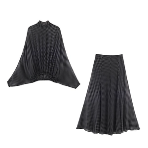 Chic two-piece women's set featuring black polka dot blouse and matching A-line midi skirt