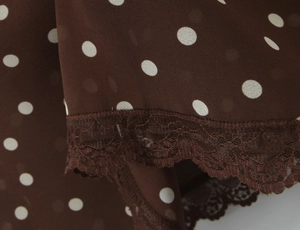 Vue macro du tissu mousseline à pois marron avec bordure en dentelle sur l'ourlet