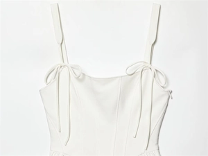 Dettaglio dell'abito a corsetto bianco con spalline sottili, fiocchi eleganti e stecche bustino