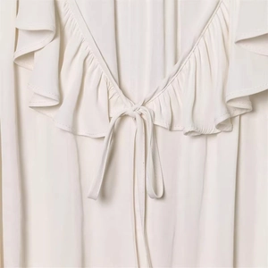 Women's off-white V-neck blouse with tiered ruffles, tie-front detail, and light texture