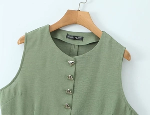 Detail view of sage green vest showing unique silver triangular buttons and fabric texture