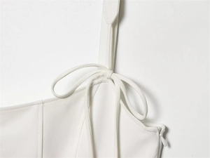 Dettaglio dell'abito bianco a corsetto con spalline sottili, fiocco e zip invisibile
