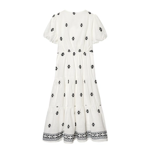 Detailed view of black floral embroidery on a white tiered dress with puff sleeves