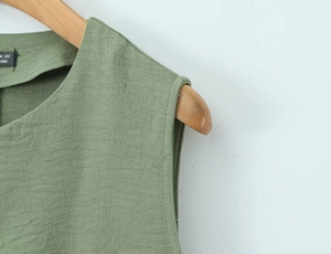 Close-up of olive green linen vest showing neck seam detail and size 6 woven label