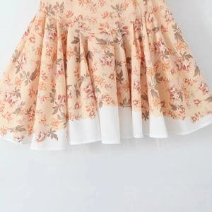 Floral print pleated mini skirt with white hem detail and vintage orange flower patterns