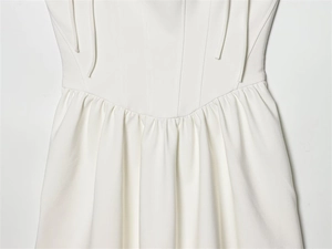 Dettaglio ravvicinato delle cuciture a corsetto e della vita a pieghe sull'abito color avorio
