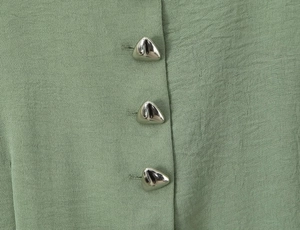 Detailed close-up of bean green fabric with unique silver triangular metal buttons