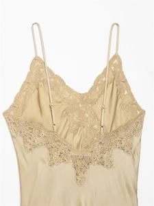 Detailed view of champagne silk slip dress with intricate lace trim and adjustable straps