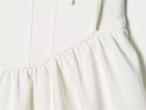 Dettaglio di un abito a corsetto bianco con stecche strutturate e gonna a pieghe