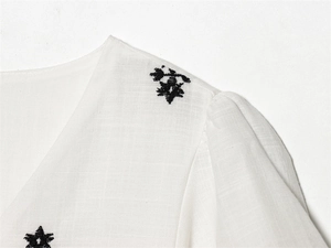 Detail view of cotton-linen fabric with black star embroidery and puffed sleeve design