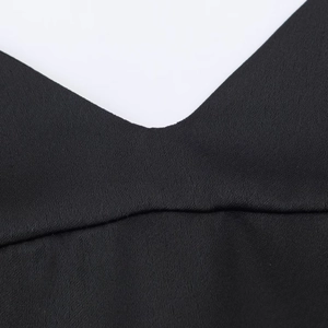 Detail of the black deep V-neckline featuring smooth satin texture and precise stitching