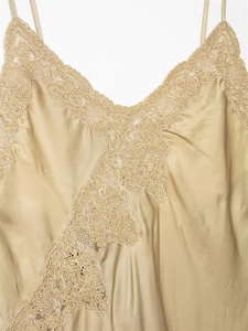 Close-up of champagne silk fabric with elegant lace trim and slim straps detail