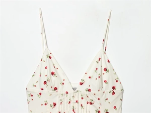 Detailed view of cream floral camisole with red roses, V-neck, and pleated fabric texture