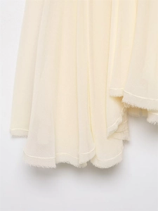 Detail view of the fine-textured ivory fabric dress featuring rustic frayed hem edges
