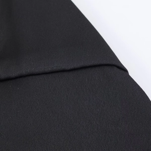 Detail shot of black satin camisole showing fine fabric texture and neat seam craftsmanship