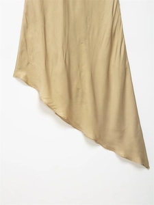 Close-up of asymmetrical hem on champagne satin dress with elegant drape and finish
