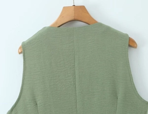 Detail view of grass green cotton linen vest back with vertical seam on wooden hanger