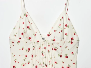 Detail view of cream floral camisole dress with pleated bodice and front buttons