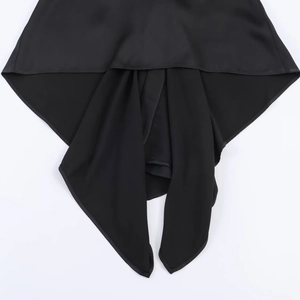 Detail of black satin asymmetric draped hemline on sleeveless top for women