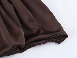 Vue macro détaillée du tissu en satin de soie marron foncé montrant la texture lisse