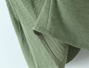 Detail view of sage green cotton linen fabric with high-quality stitching and texture