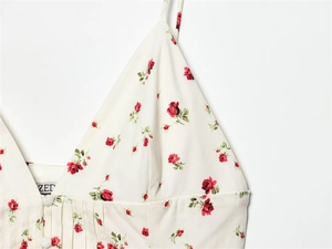 Detail of V-neck white camisole with red rose print, pleats and decorative buttons
